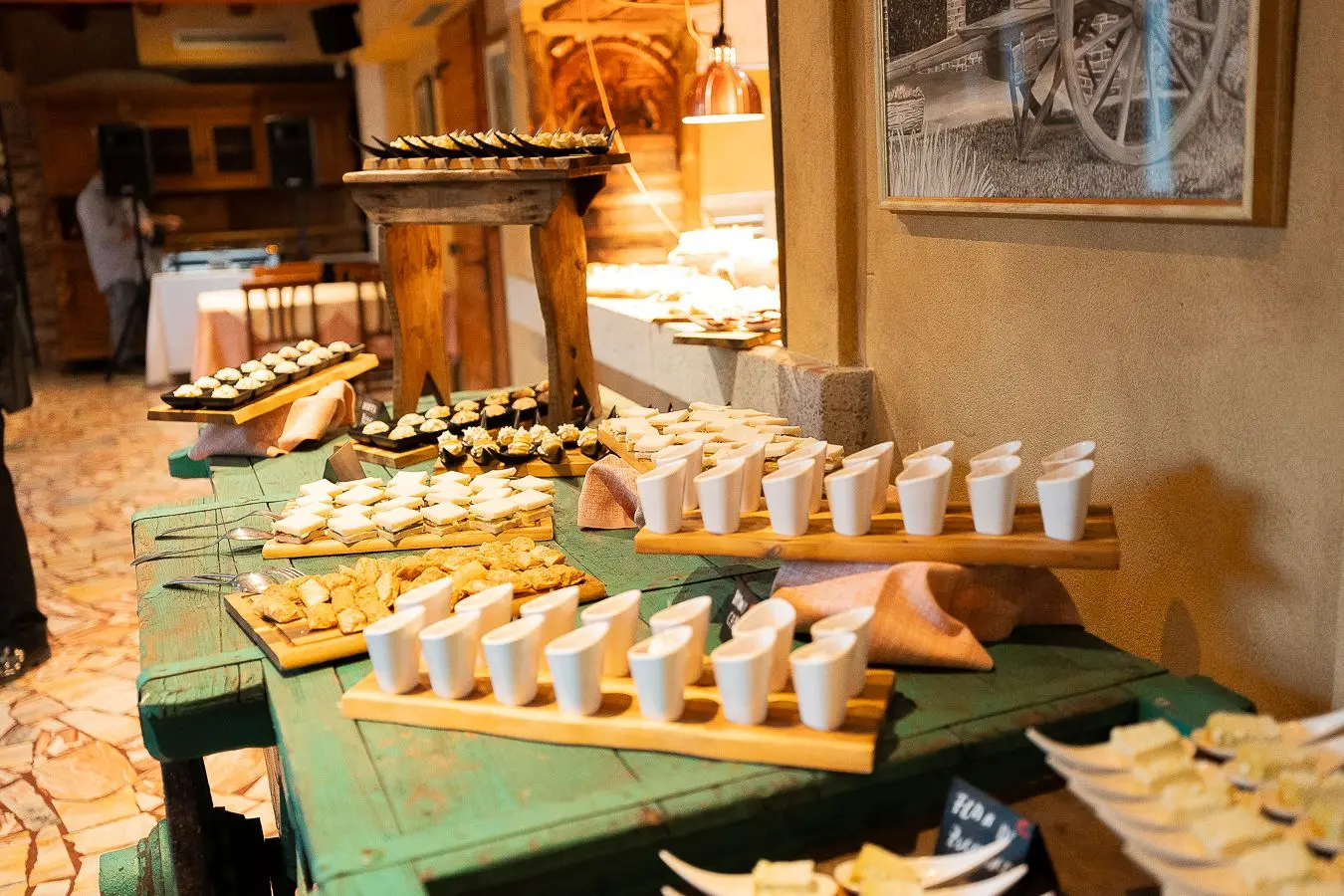 Buffet di finger food e monoporzioni disposto su tavoli rustici nella Veranda
