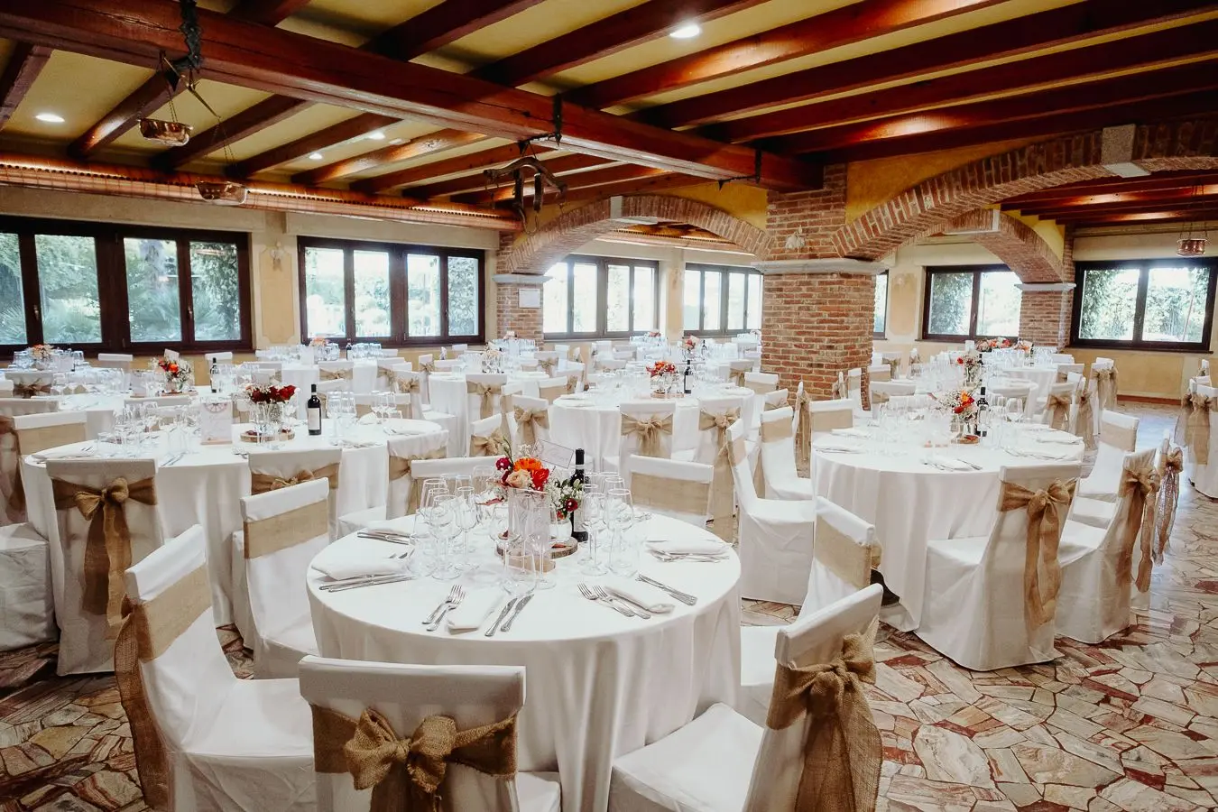 Allestimento elegante del Gran Salone con tavoli rotondi e dettagli rustici