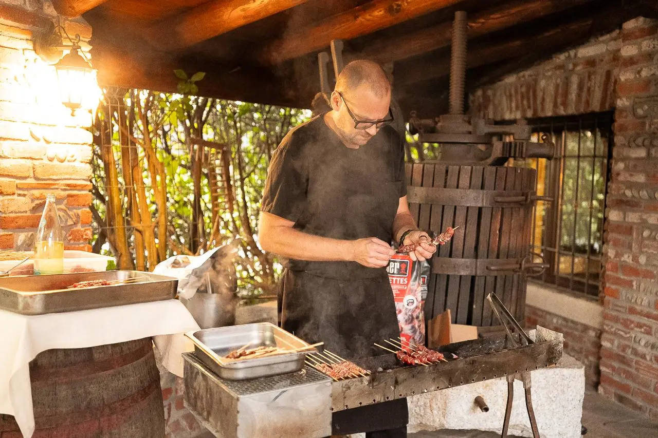 Cuoco prepara arrosticini alla griglia durante il buffet di matrimonio