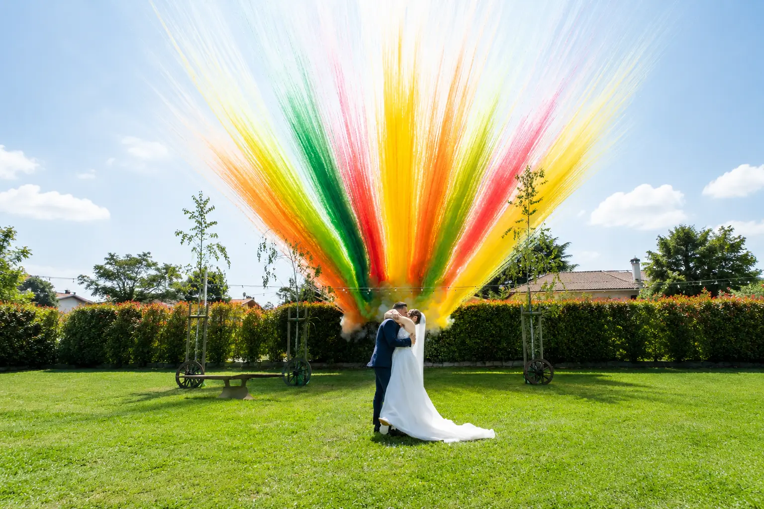 Sposi si baciano nel prato davanti a una grande esplosione di fumogeni colorati