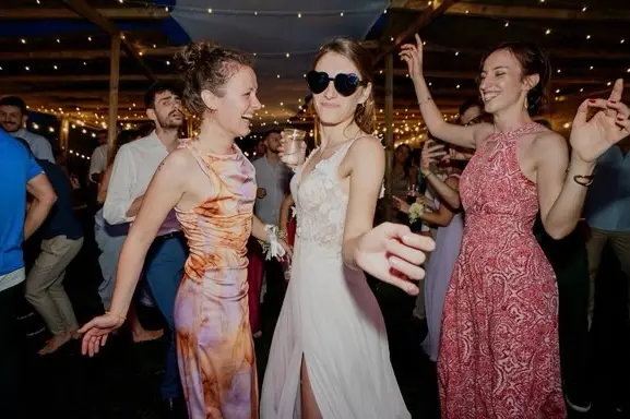 Sposa e invitate ballano durante la festa serale sotto le luci della Tela Verde