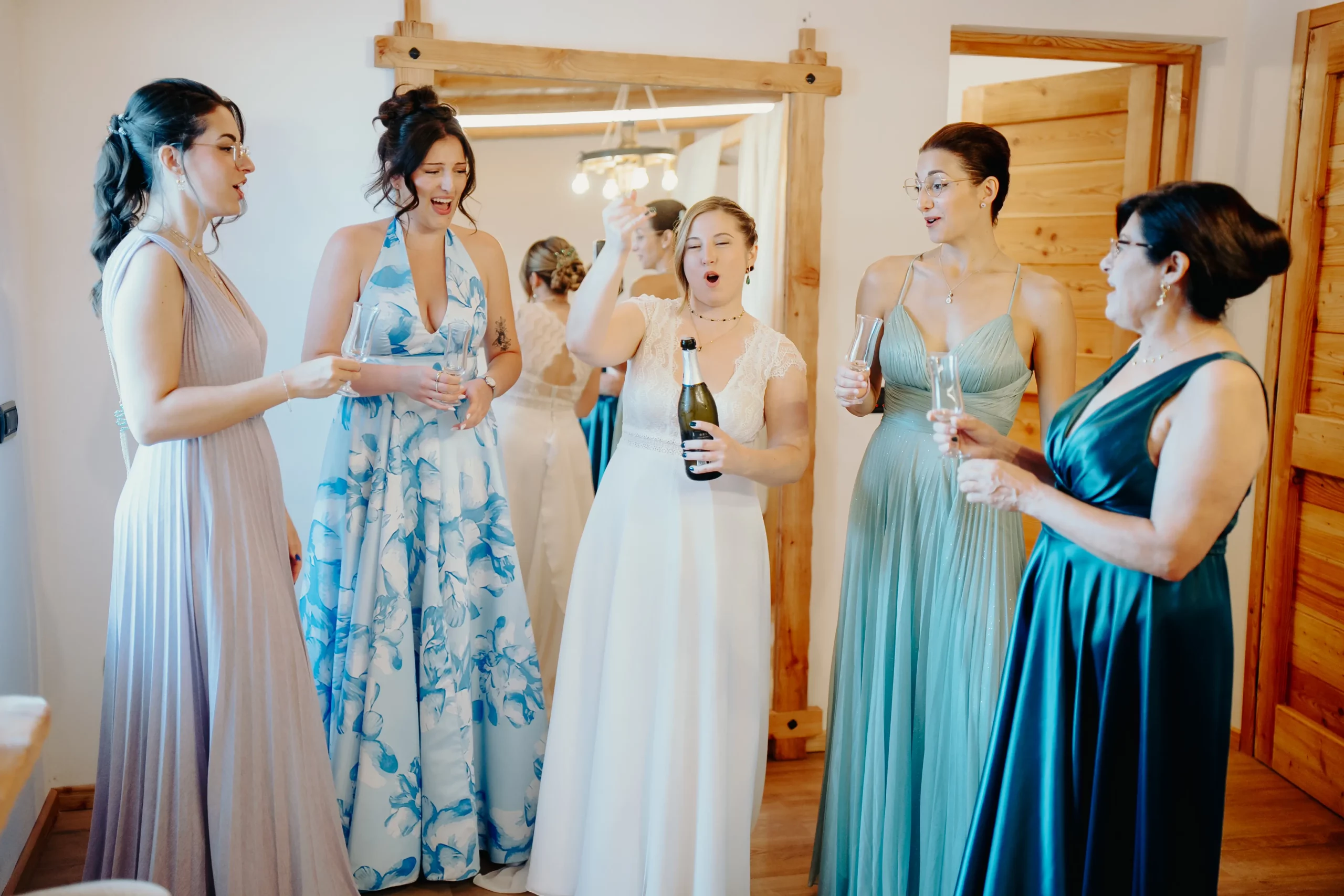 Sposa brinda con amiche e familiari durante i preparativi nella camera della location