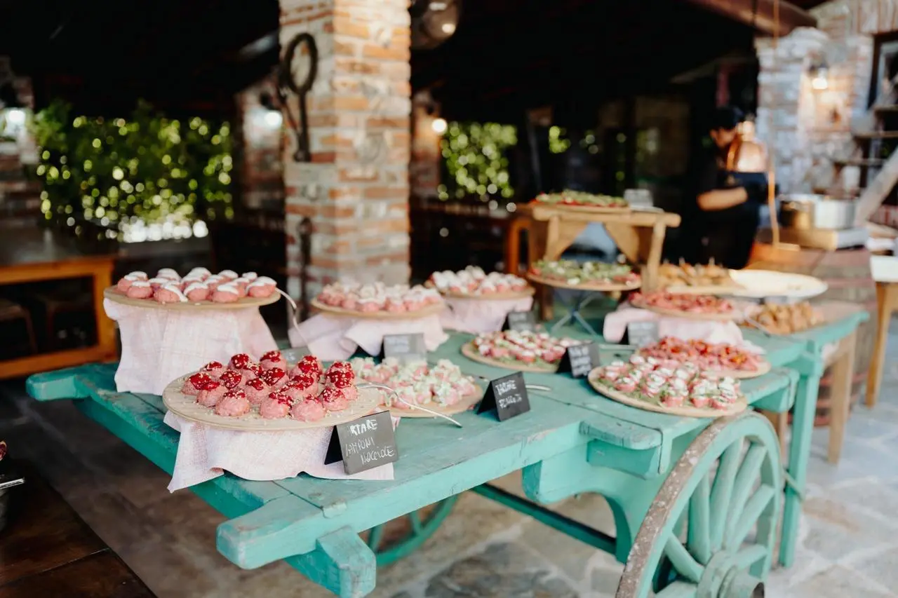 Buffet di dolci e piccola pasticceria allestito su un carretto verde