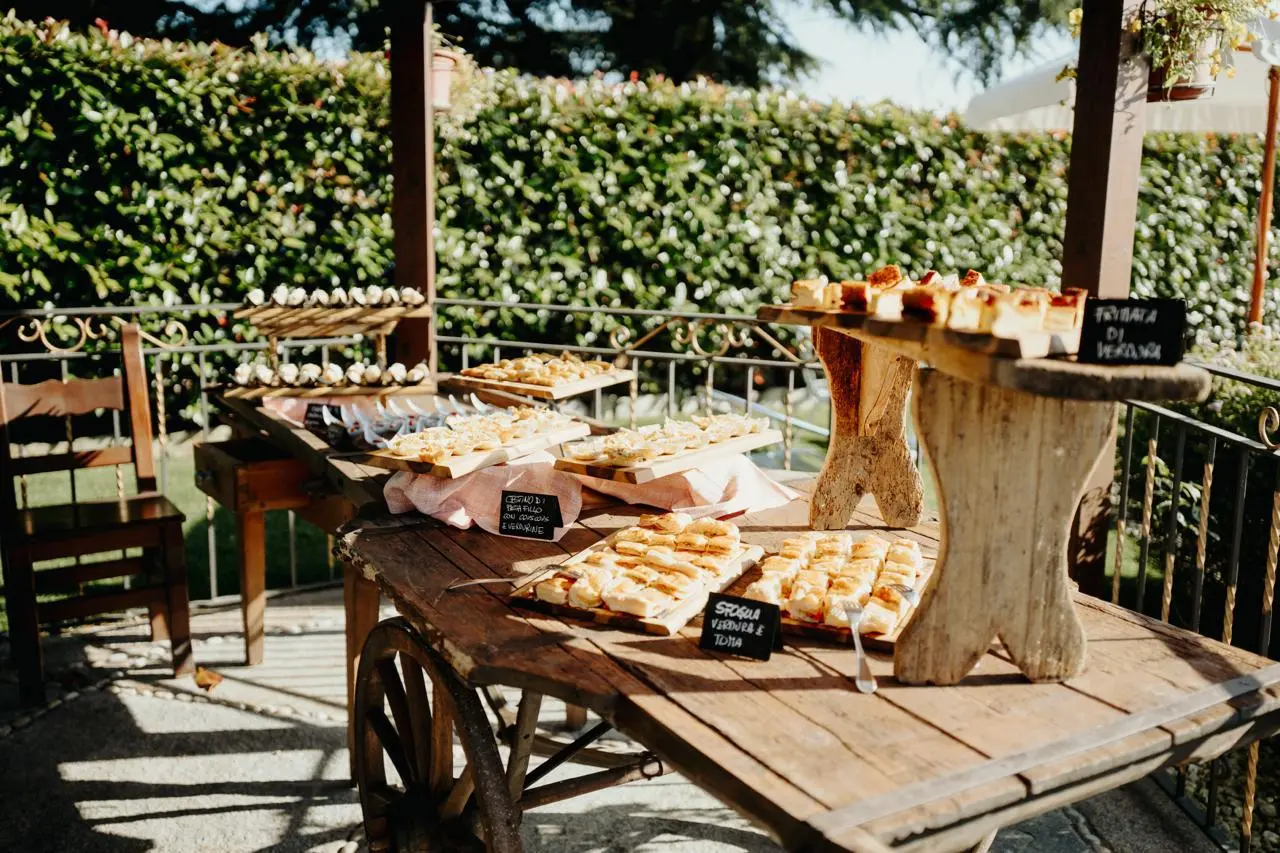 Buffet salato allestito su tavoli rustici nel porticato della location