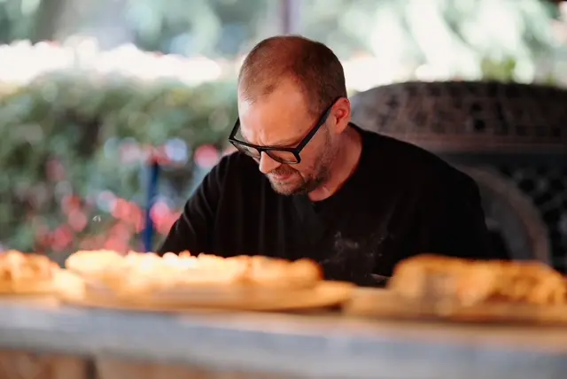 Cuoco al lavoro durante la preparazione del buffet nel porticato