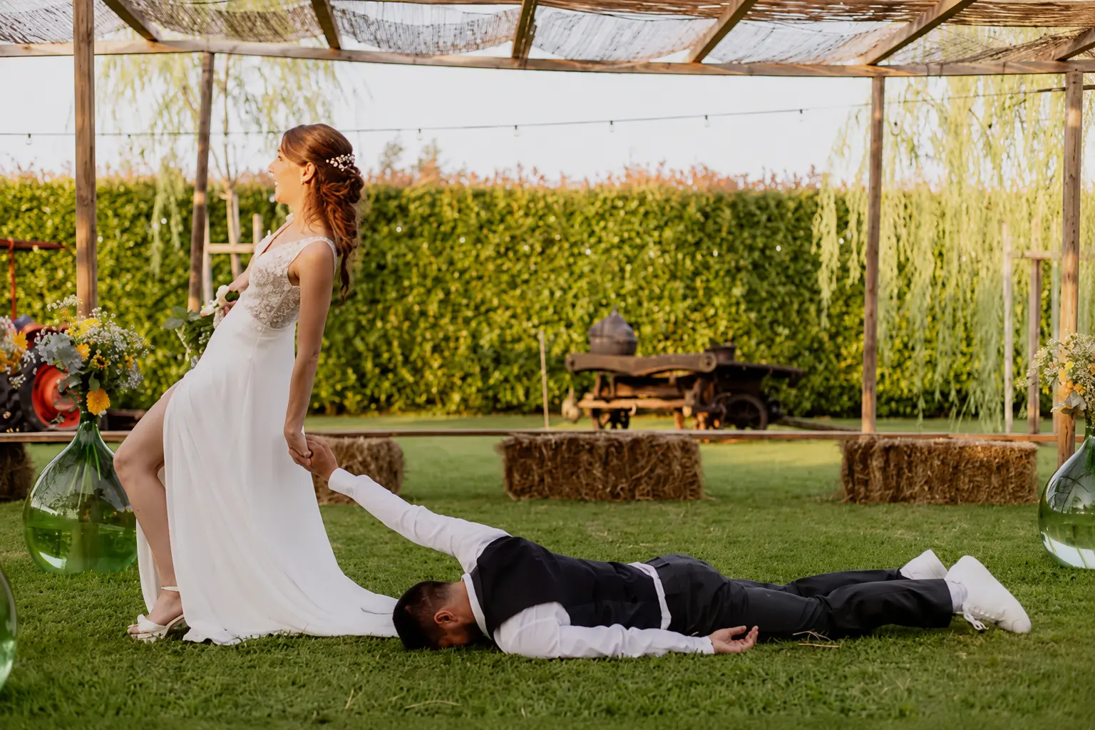Sposa trascina scherzosamente lo sposo sdraiato sul prato della Tela Verde