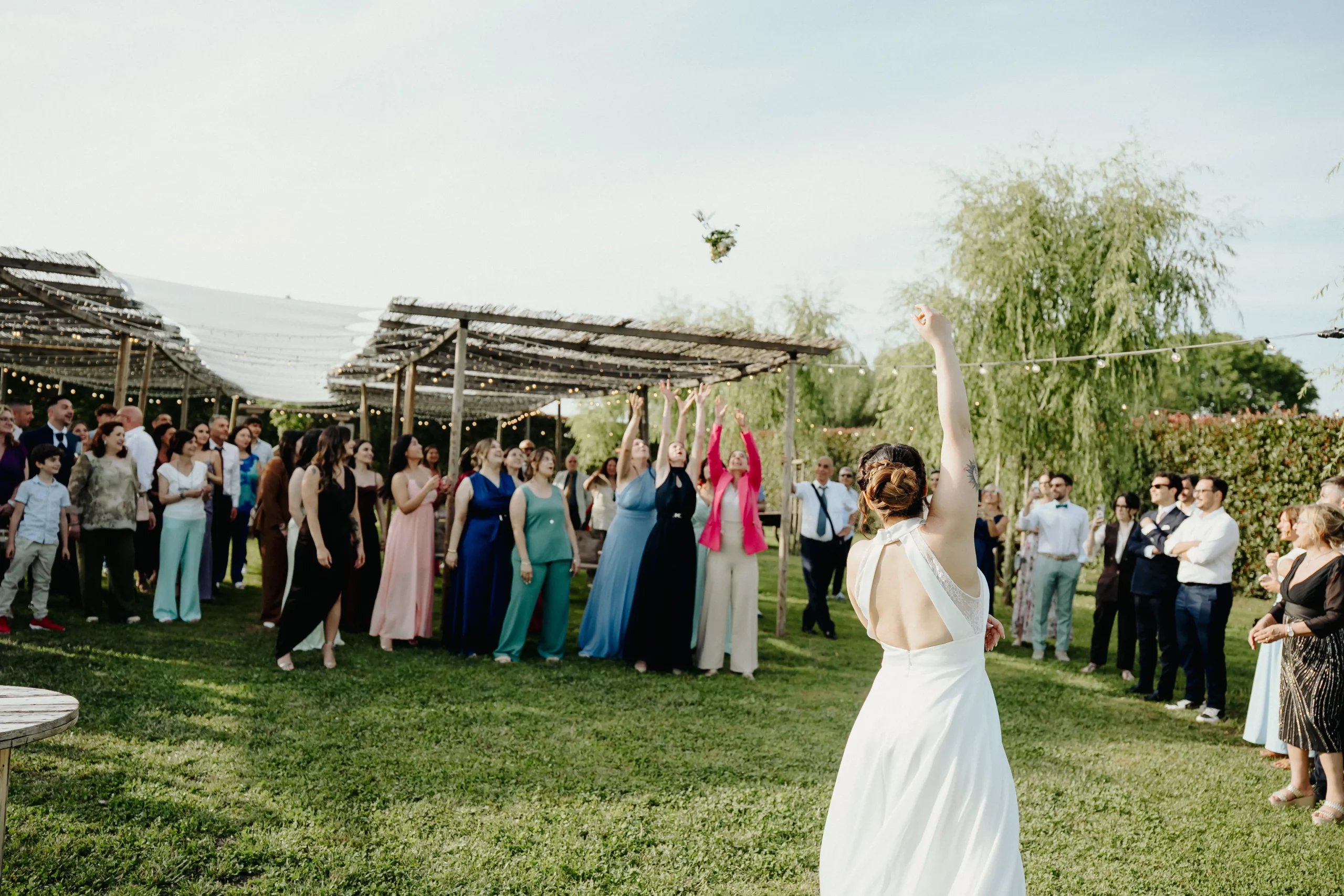 Sposa lancia il bouquet alle invitate nel giardino della Tela Verde