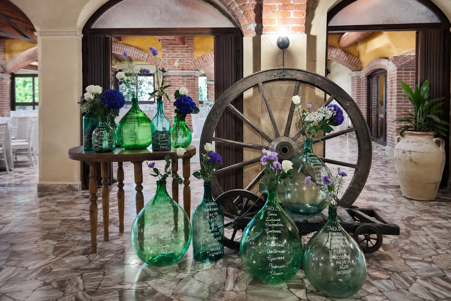 Tableau mariage con damigiane verdi e ruota in legno nella Sala Volte a Oleggio