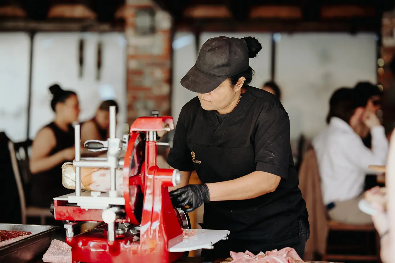 Addetta prepara salumi freschi con affettatrice durante il buffet di matrimonio