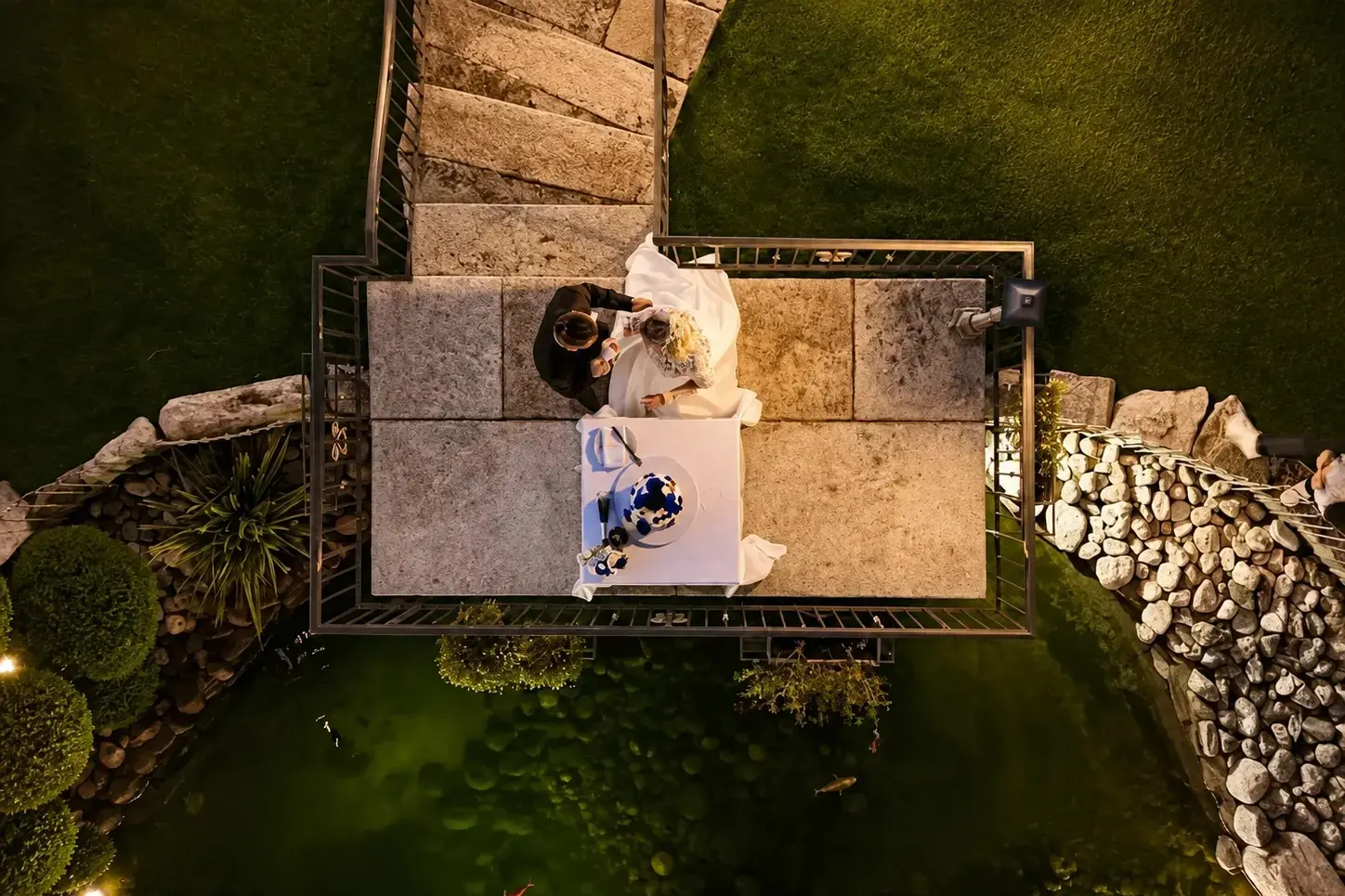 Vista dall’alto degli sposi sul ponte del laghetto durante il taglio della torta