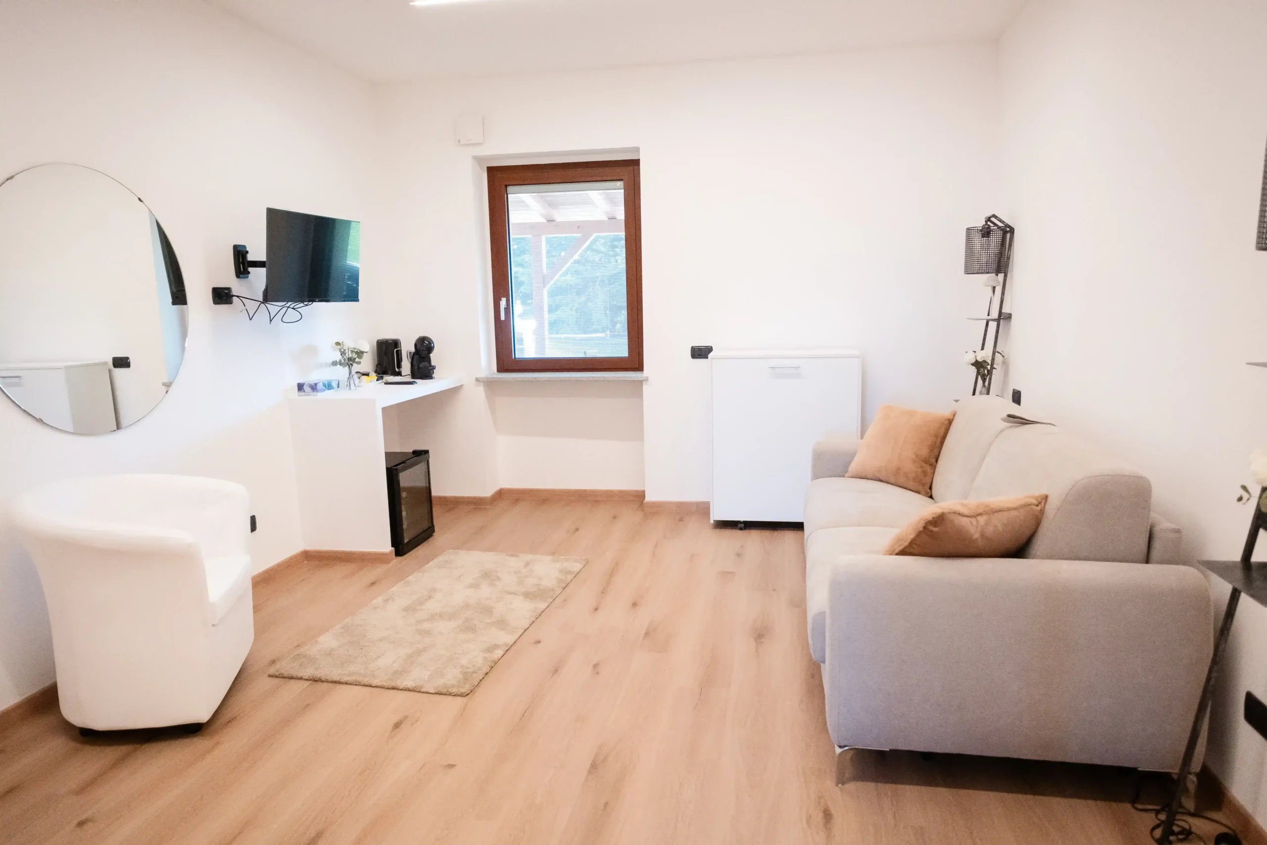 Zona relax della camera con divano, poltrona, televisione e angolo ristoro