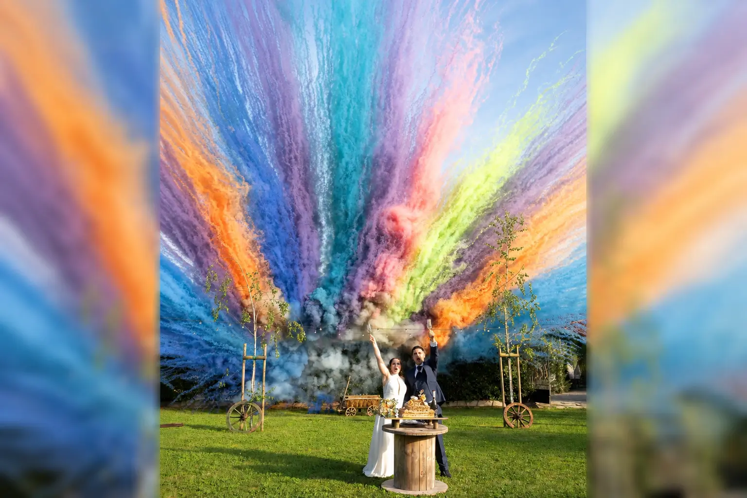 Sposi festeggiano davanti alla torta nuziale con fumogeni colorati nel giardino