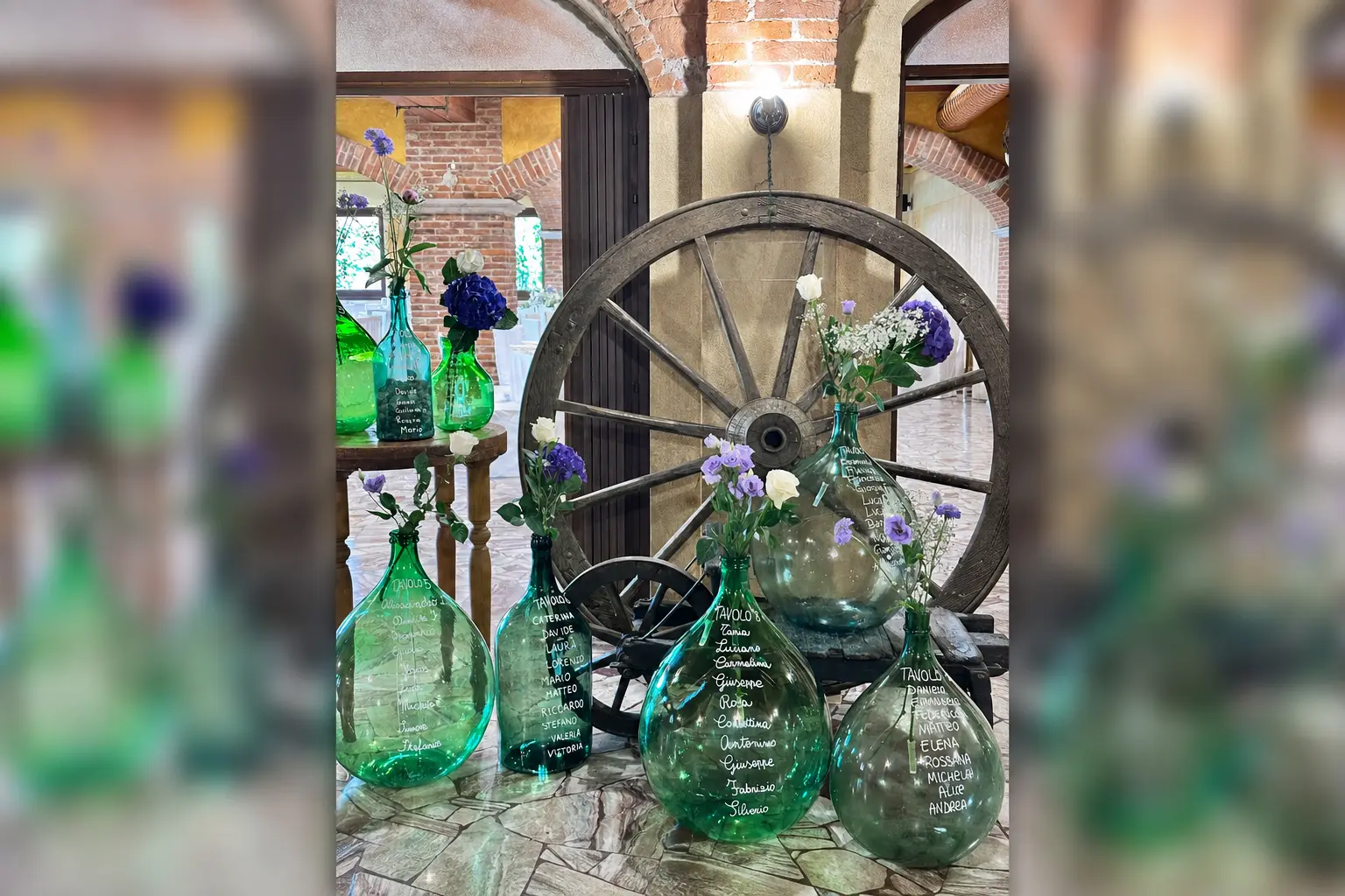 Tableau mariage con damigiane verdi e ruota in legno nella Sala Volte a Oleggio